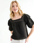 Woman wearing a black blouse with ruffled sleeves on a white background
