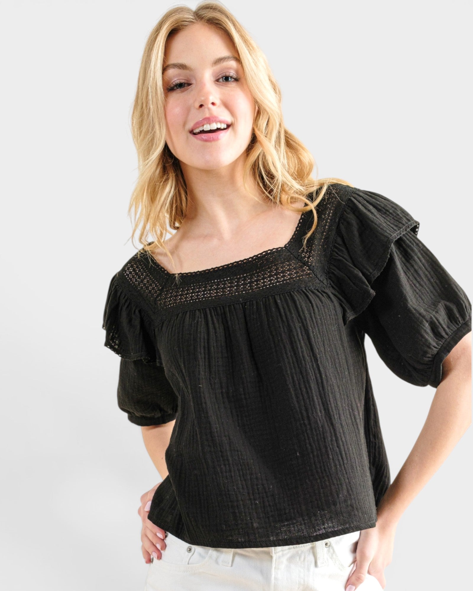 Woman wearing a black blouse with ruffled sleeves on a white background