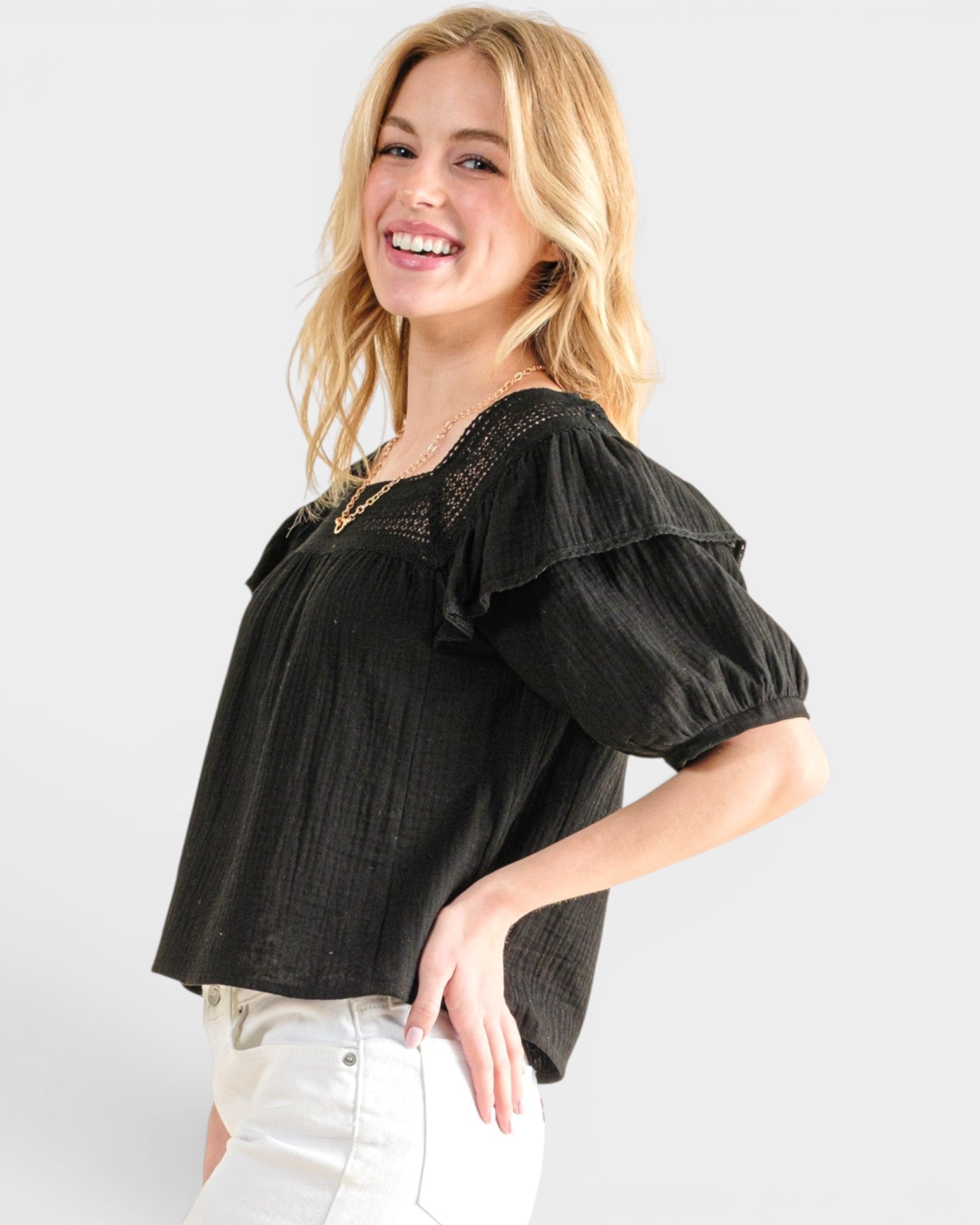 Woman wearing a black blouse with ruffled sleeves on a white background