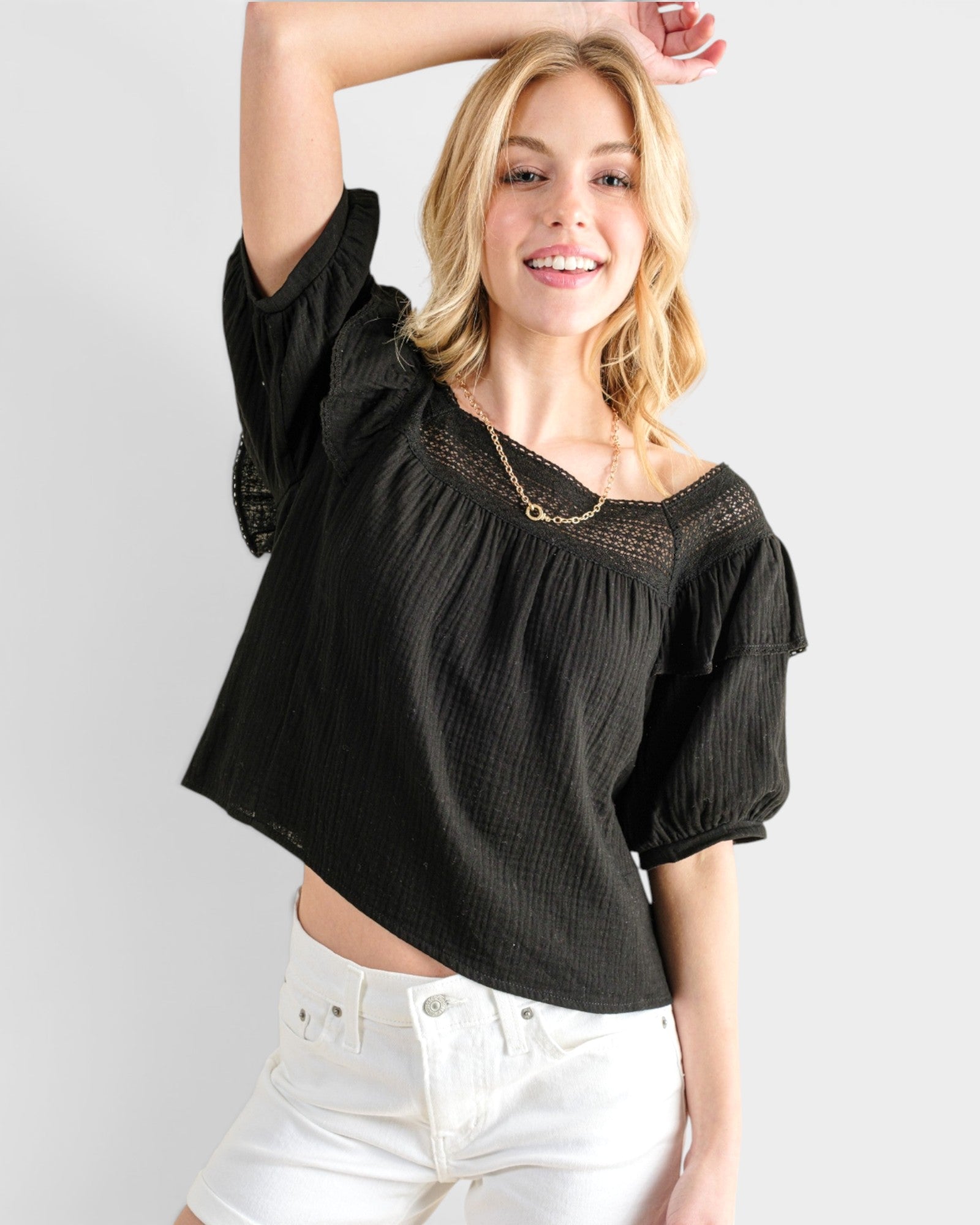 Woman wearing a black blouse with puff sleeves against a white background