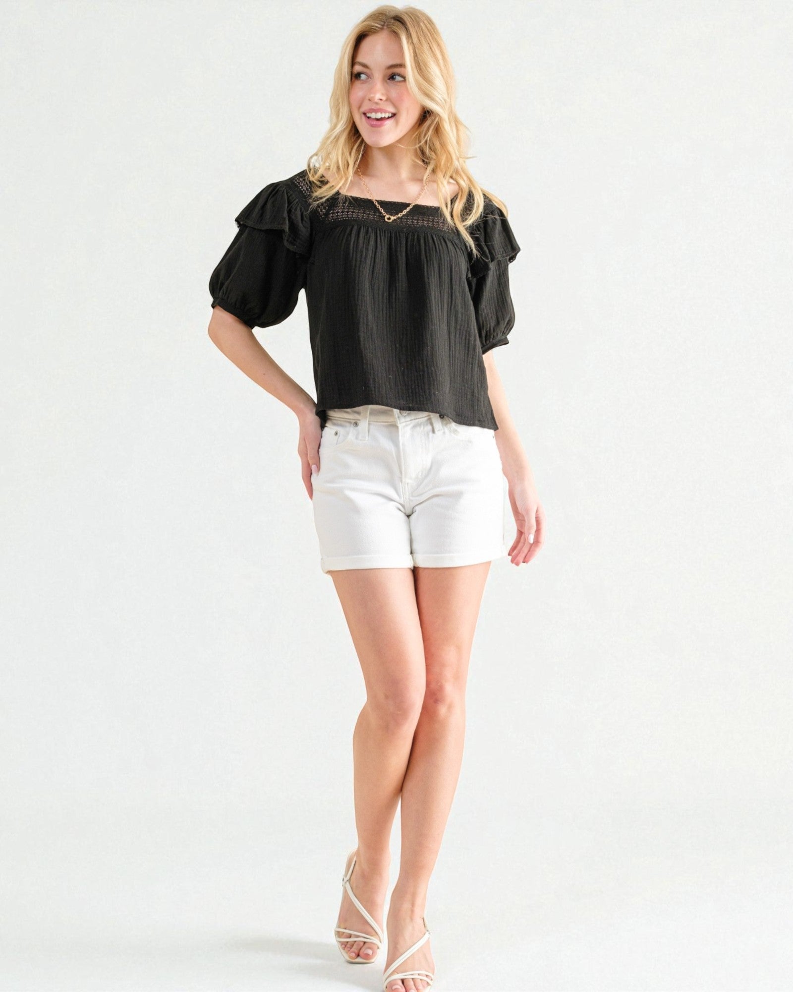 Woman wearing a black top and white shorts on a white background
