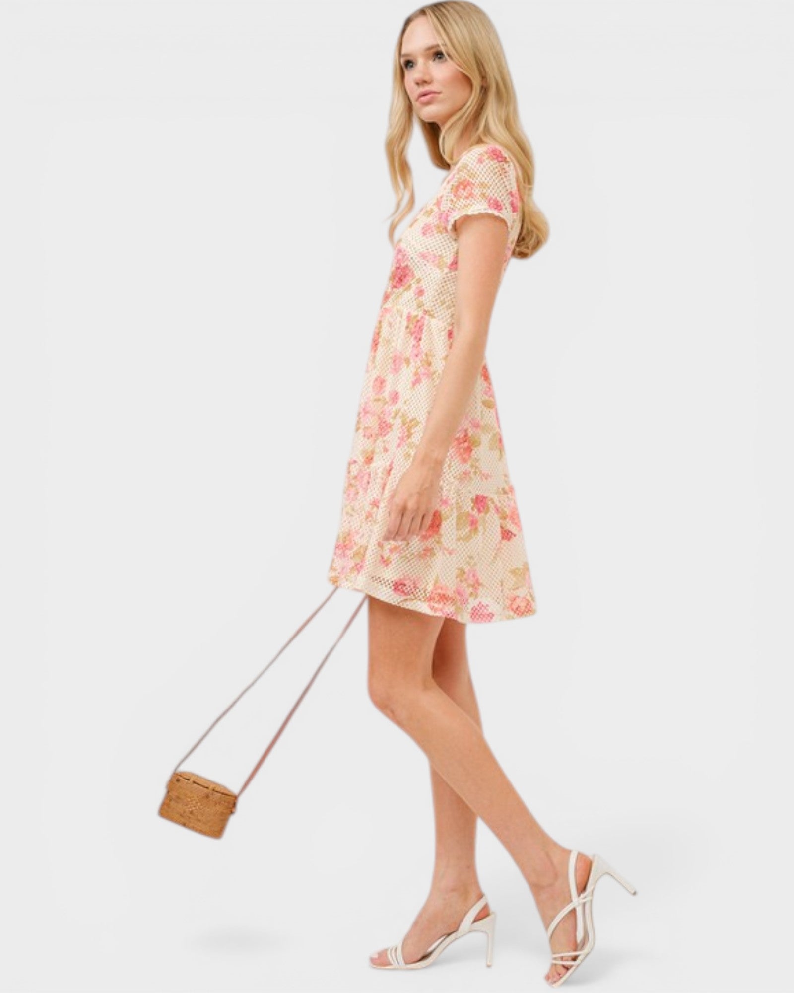 Woman wearing a floral dress holding a handbag on a white background