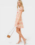 Woman wearing a floral dress holding a handbag on a white background