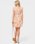 Woman wearing a floral dress holding a straw bag on a white background