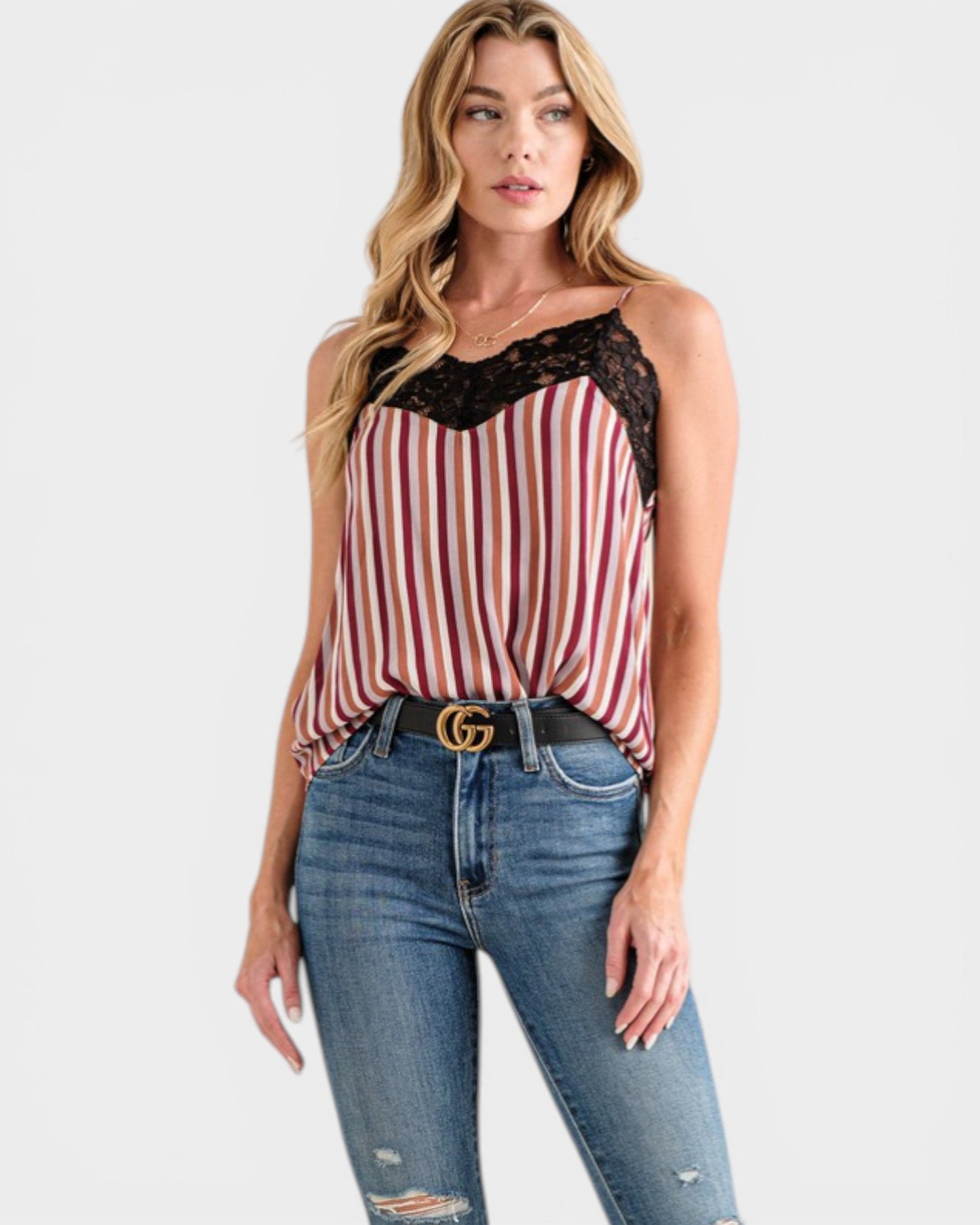 Woman wearing a striped tank top with lace details and blue jeans on a white background