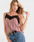 Woman wearing a striped tank top with lace details and blue jeans on a white background