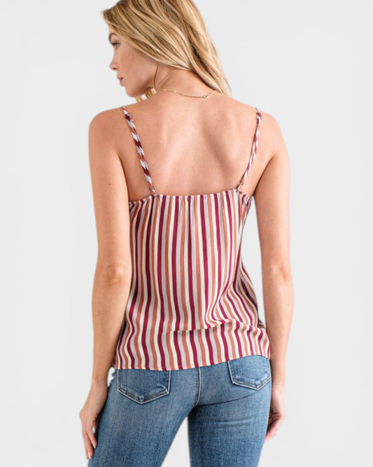 Woman wearing a red and white striped tank top and blue jeans on a light gray background