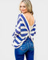 Woman wearing a blue and white striped top with a backless design, standing against a plain background.