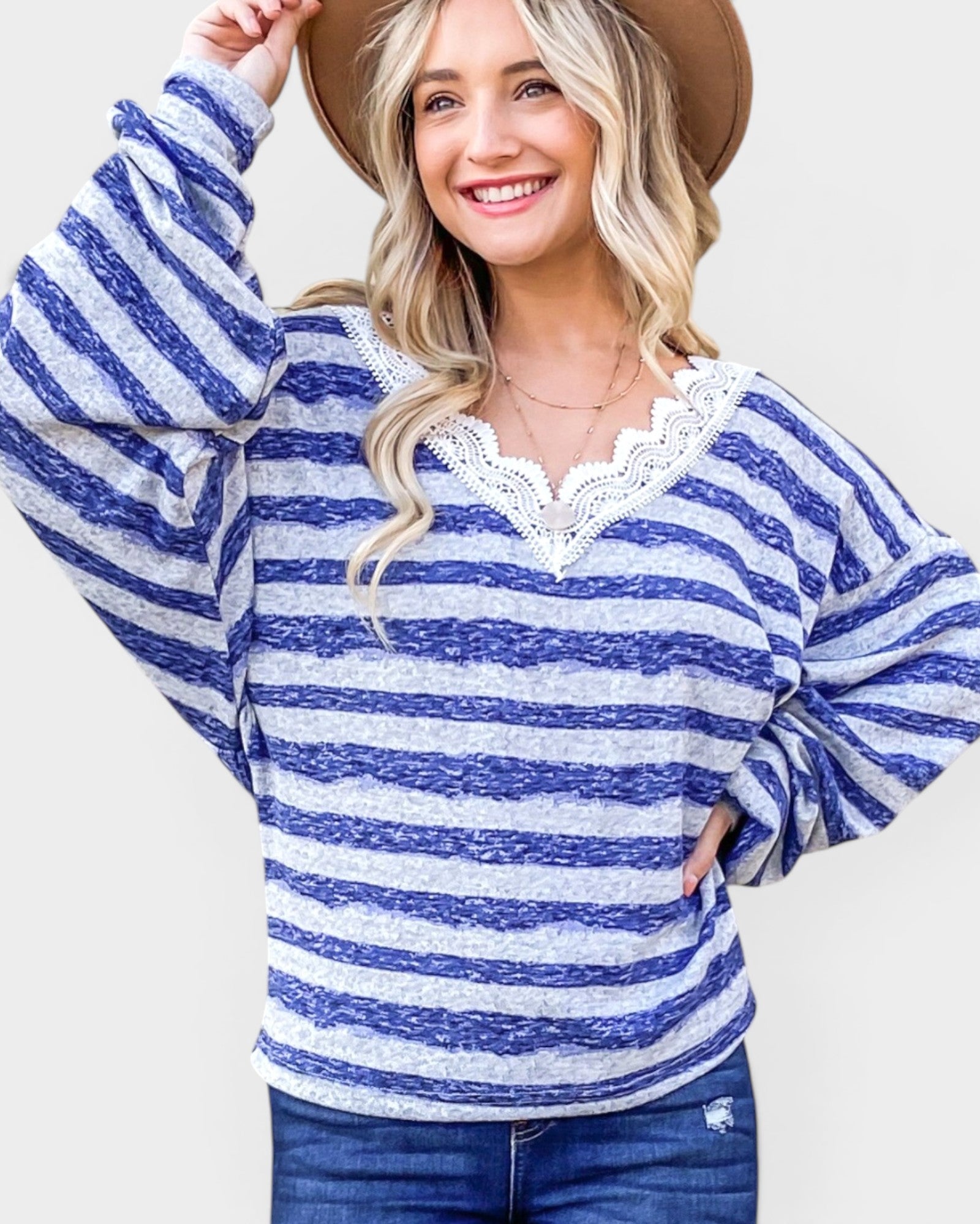 Woman wearing a blue and white striped sweater with lace details on a white background