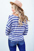 Woman wearing a blue and white striped sweater with a beige hat on a white background