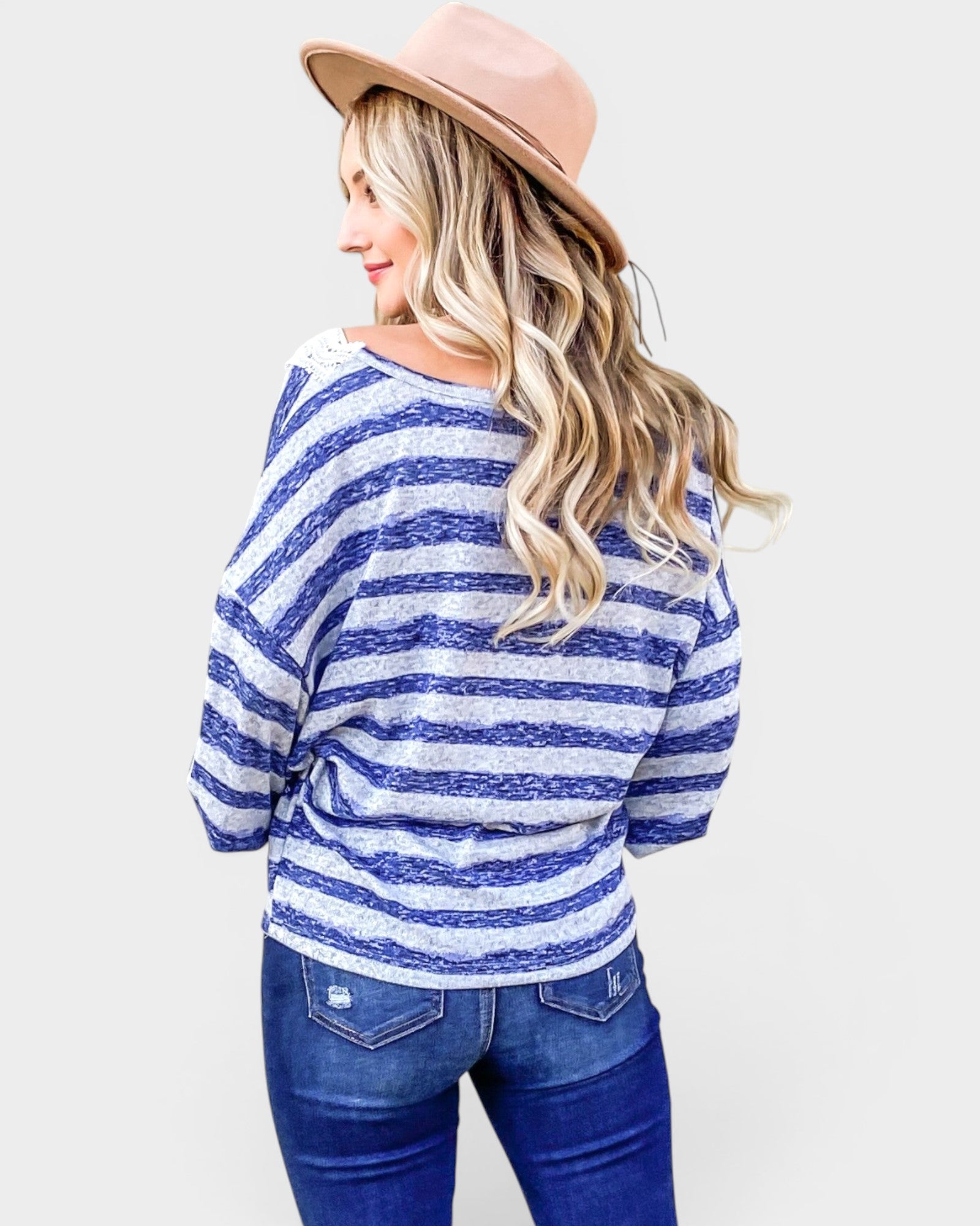 Woman wearing a blue and white striped sweater and jeans with a pink hat on a white background