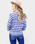 Woman wearing a blue and white striped sweater and jeans with a pink hat on a white background