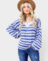 Woman wearing a blue and white striped shirt with bell sleeves on a plain background