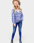 Woman wearing a blue and white striped sweater and jeans on a white background