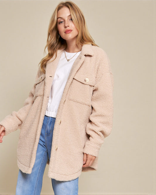 Woman wearing a beige coat over a white shirt and blue jeans on a beige background