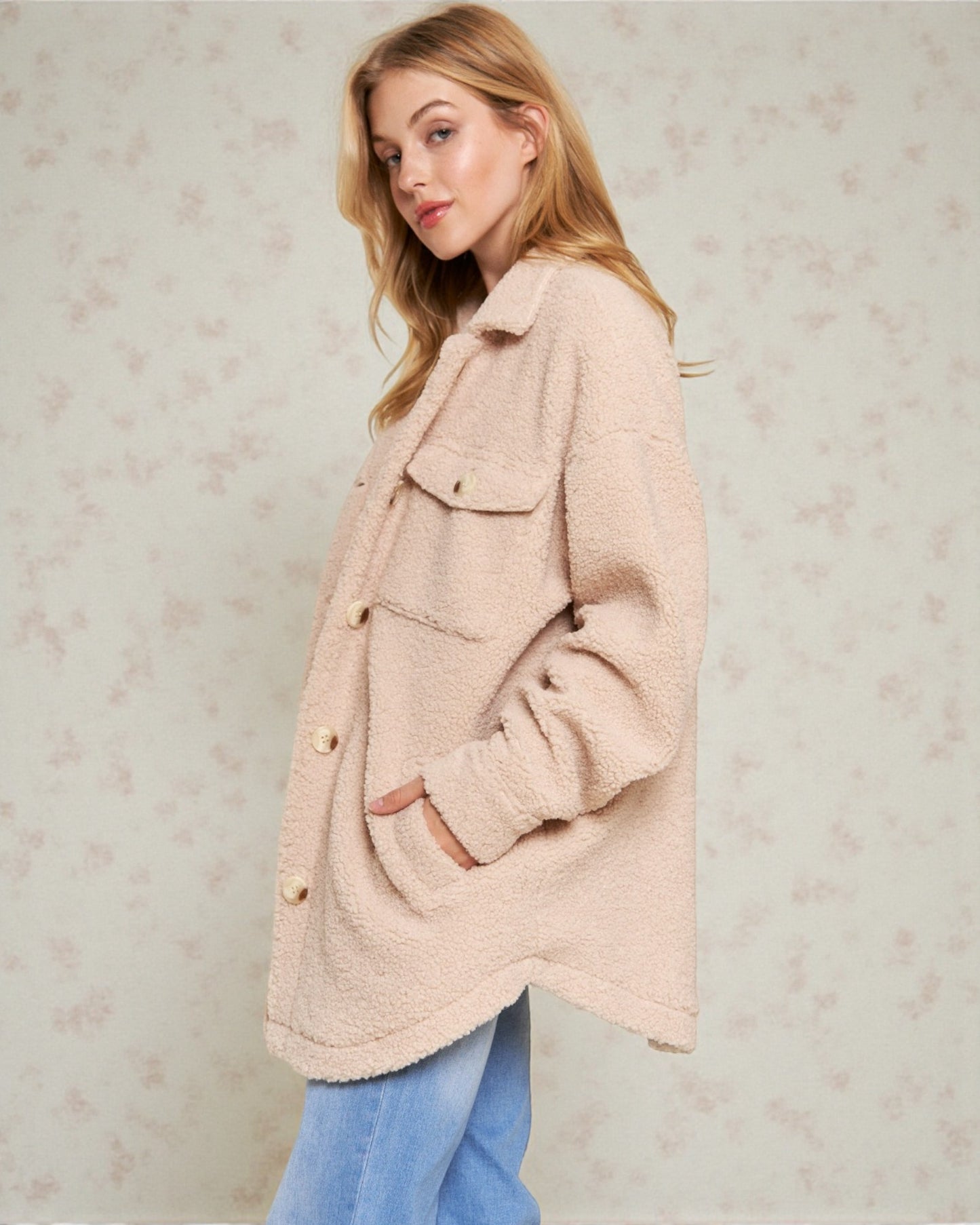 Woman wearing a light pink coat against a neutral background