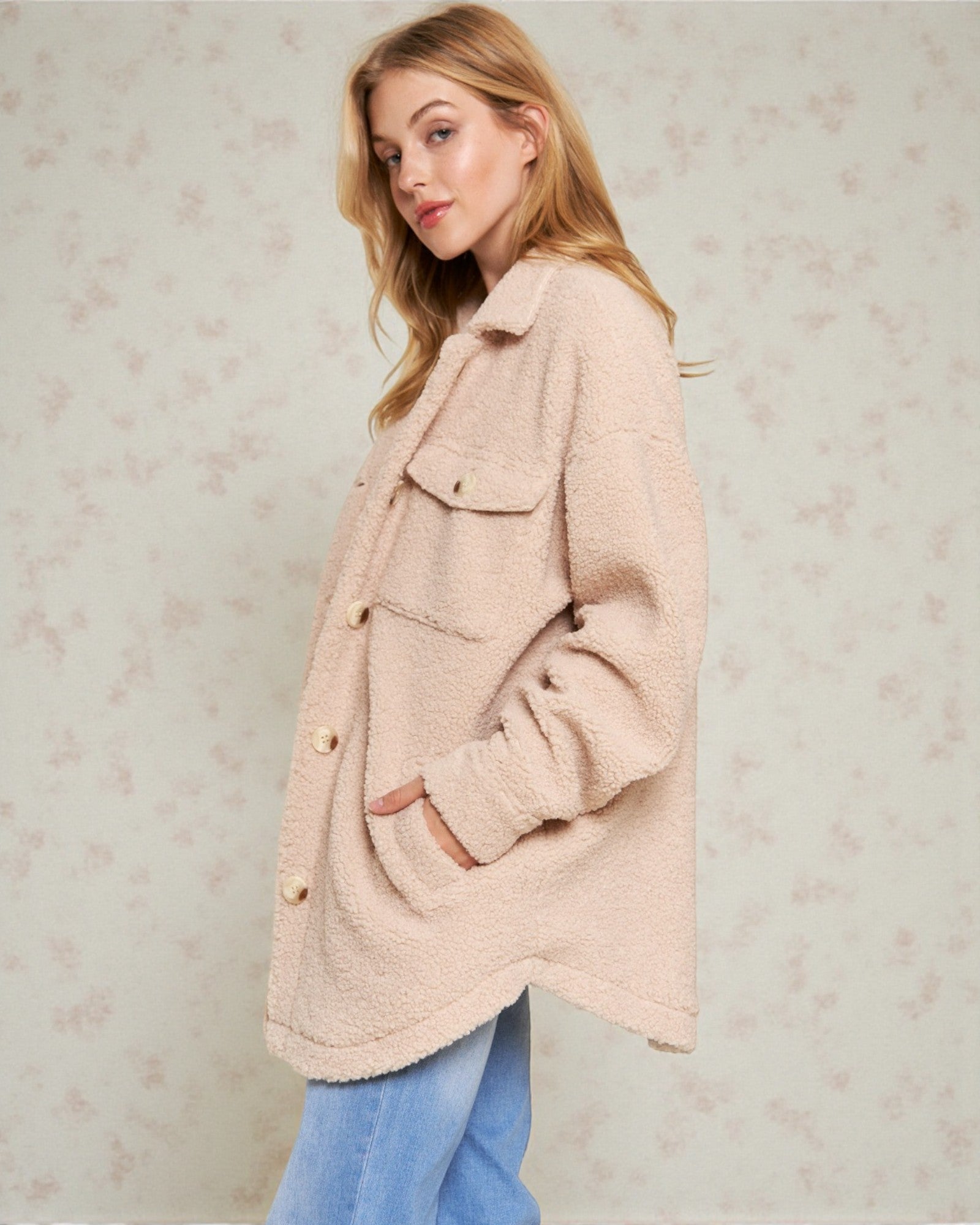 Woman wearing a light pink coat against a neutral background