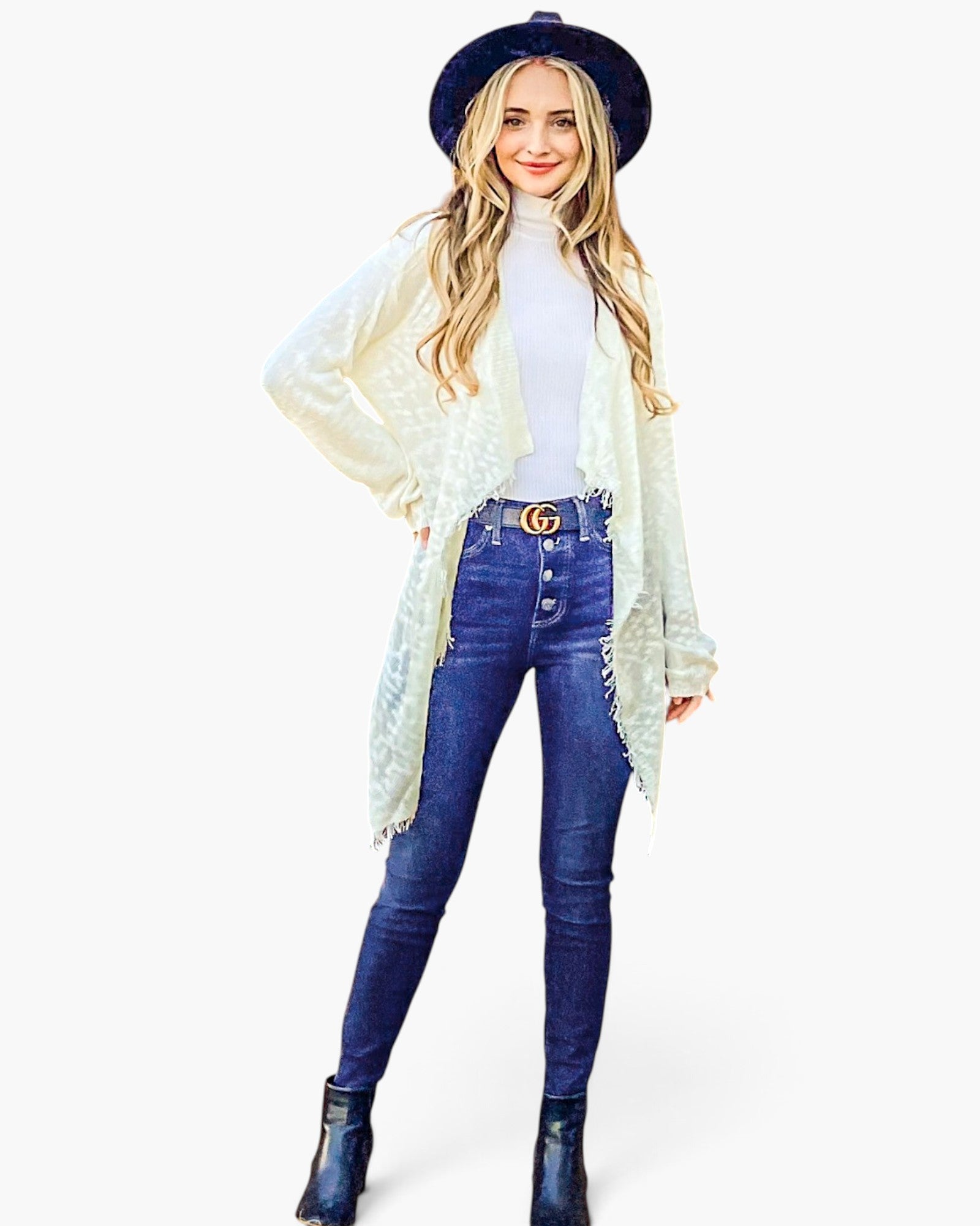 A woman modeling a white lace long-sleeve cardigan over a white turtleneck, paired with blue skinny jeans, a Gucci belt, a black wide-brim hat, and black ankle boots, against a plain white background.