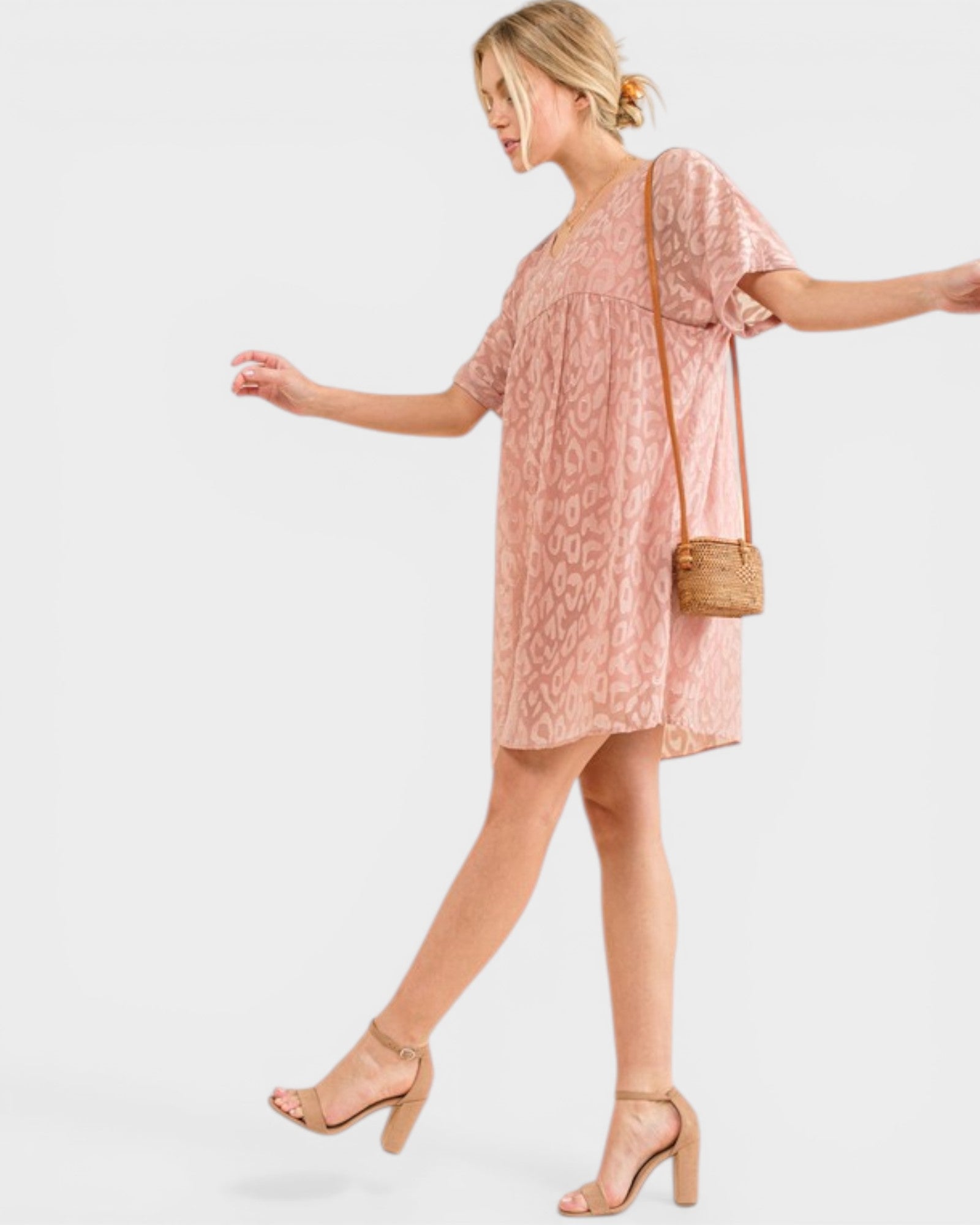 Woman wearing a pink lace dress with a plain background