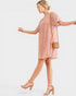 Woman wearing a pink lace dress with a plain background