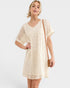 Woman wearing a beige dress with a plain background