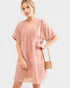 Woman wearing a pink patterned dress with a neutral background