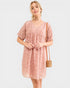 Woman wearing a pink patterned dress with a white background