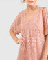 Woman wearing a pink patterned dress with a plain background