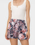 Person wearing a white tank top and floral shorts on a plain background