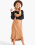 A woman modeling a tan midi dress with a black long-sleeve top layered underneath, wearing a brown wide-brim hat against a plain white studio background.