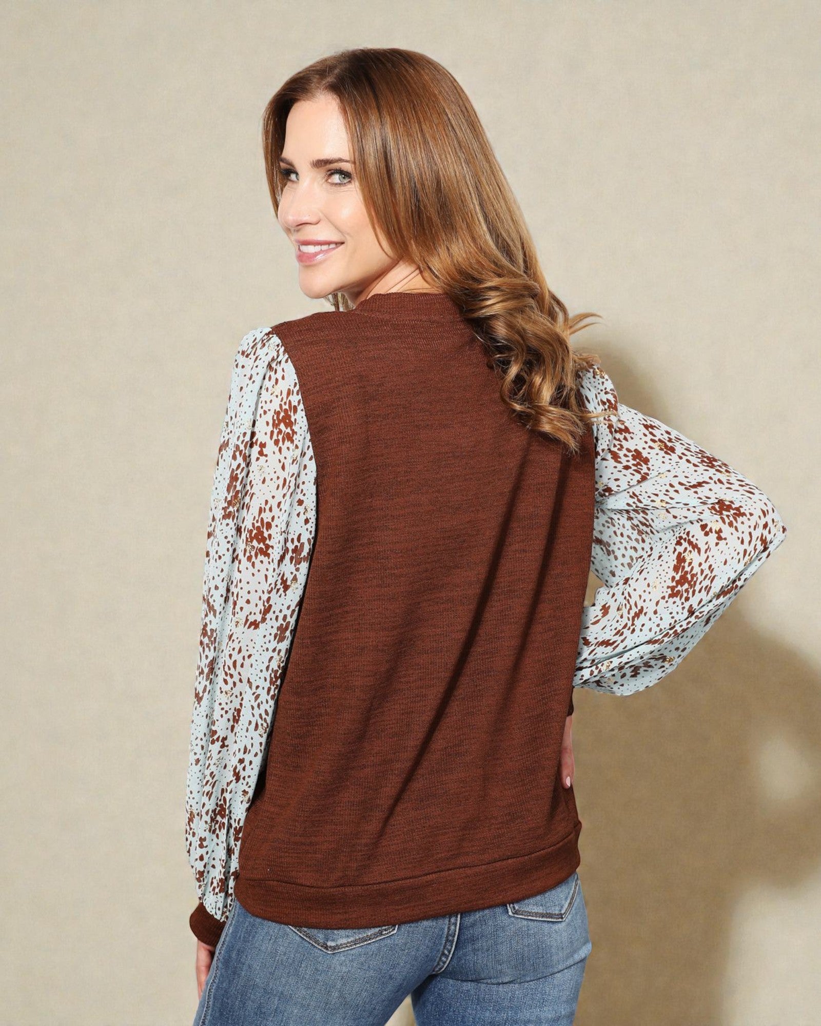 Woman wearing a brown vest over a floral shirt with a beige background