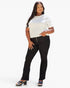 A woman modeling black high-waisted straight-leg pants with three front buttons, paired with a white short-sleeve top and black platform sandals, against a plain white studio background.