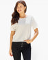 A woman wearing a white short-sleeve crewneck top and black pants, standing against a plain white background.