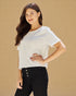 Woman wearing a white blouse and black pants against a beige background