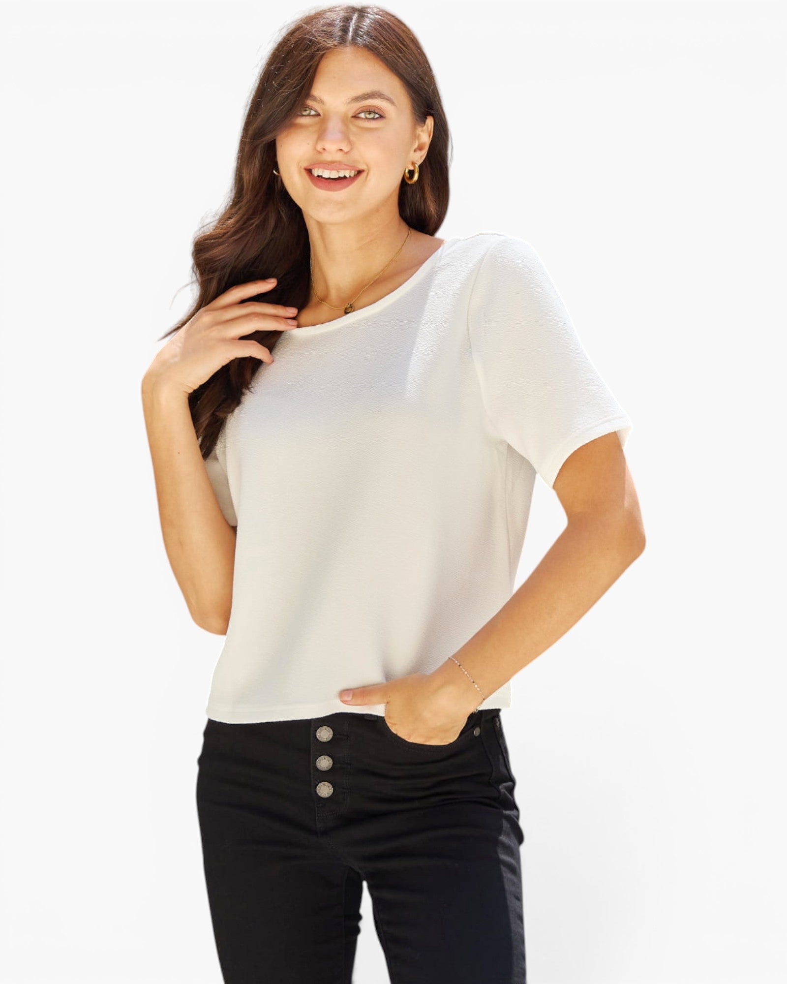 A woman modeling a short-sleeve scoop-neck top in off-white, paired with black high-waisted jeans featuring a button fly, against a plain white studio background.