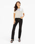 A woman modeling a white short-sleeve top and black high-waisted straight-leg jeans with front buttons, paired with black sandals, against a plain white studio background.