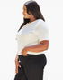 A woman wearing a fitted white short-sleeve top and black pants, shown in side profile against a plain light background.