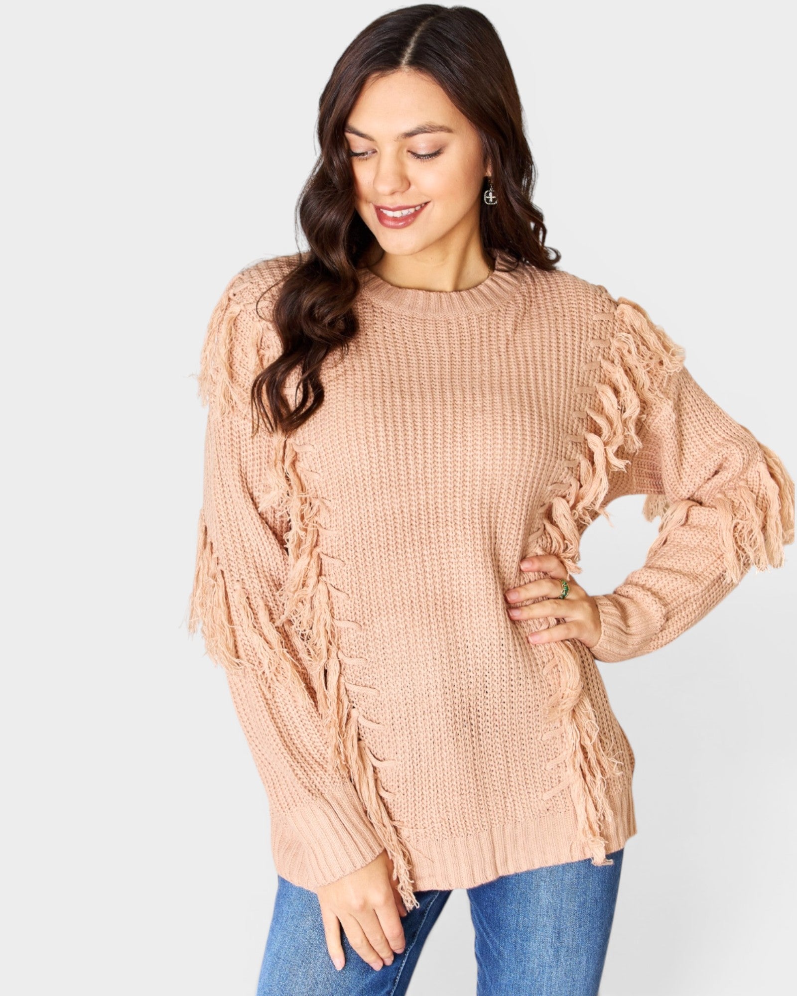 Woman wearing a beige cable knit sweater with ruffled sleeves on a white background