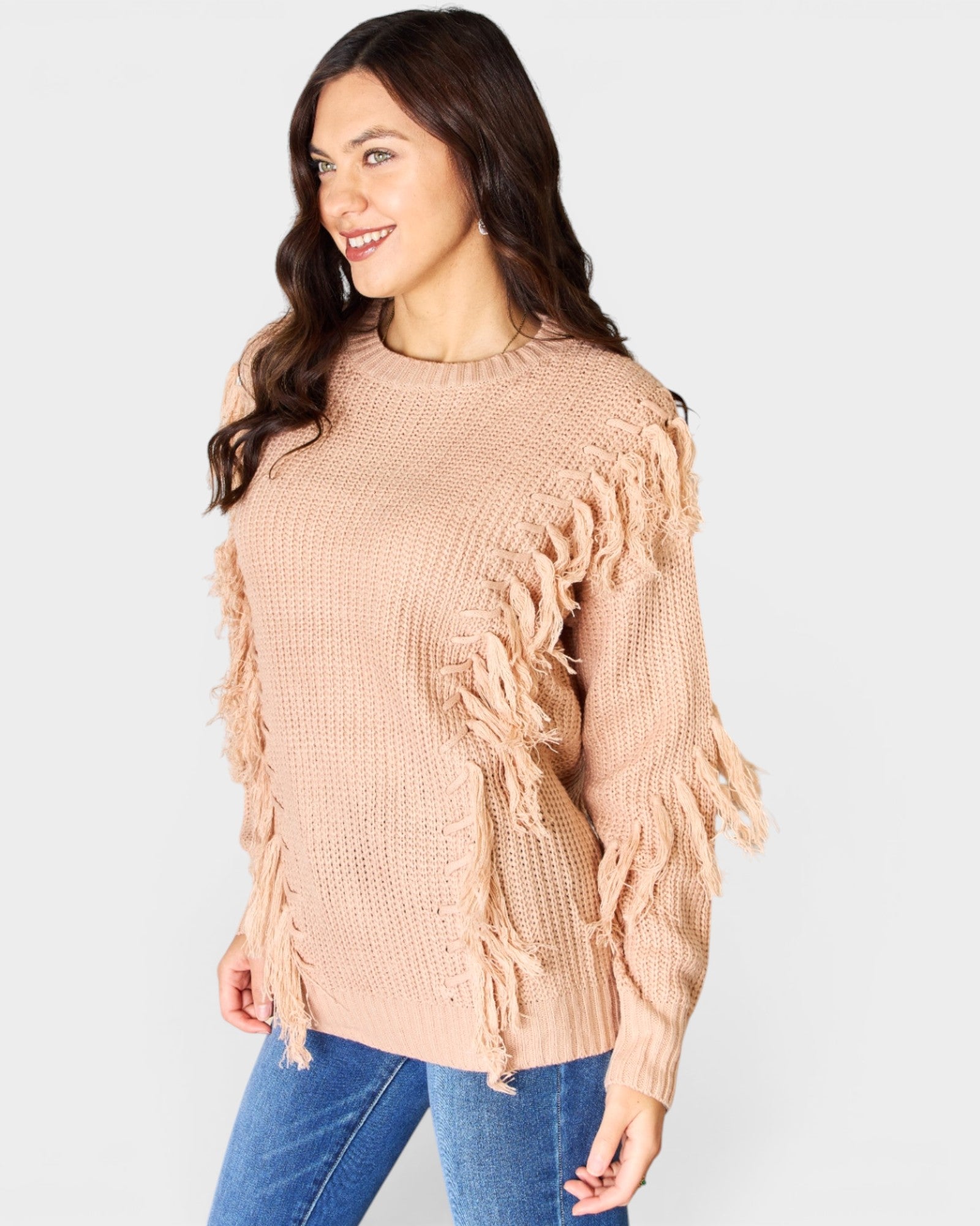 Woman wearing a beige fringed sweater against a light gray background