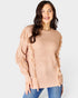 Woman wearing a beige cable knit sweater with ruffled sleeves on a white background