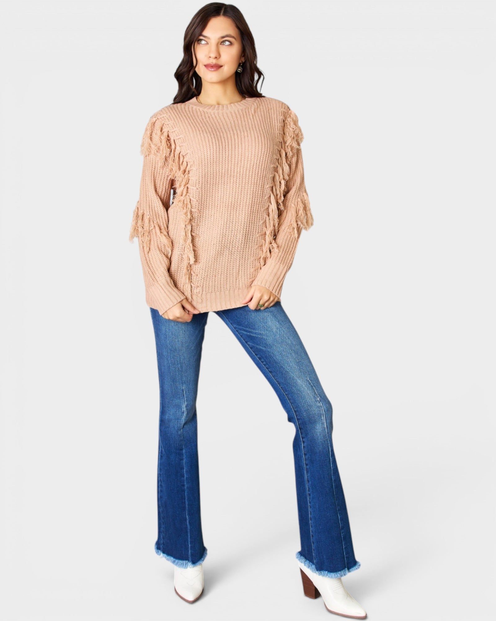 Woman wearing a beige sweater and blue jeans on a white background