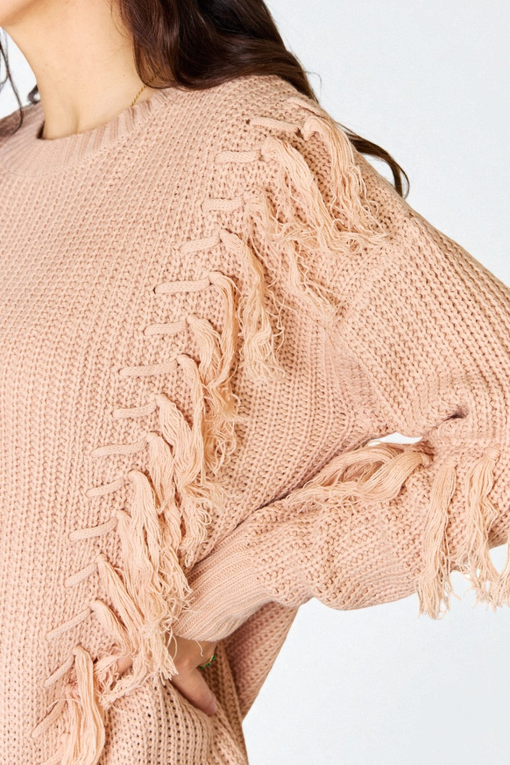 Close-up of a beige knitted sweater with intricate patterns on a white background