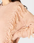 Close-up of a pink knitted cardigan with fringe details on a white background