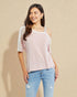 Woman wearing a light pink top and blue jeans against a beige background