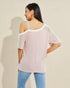 Woman wearing a light pink off-shoulder top with sheer sleeves against a beige background