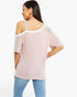 A woman shown from the back wearing a light pink cold-shoulder top with white trim and light gray sleeve panels, paired with blue jeans, against a plain white background.