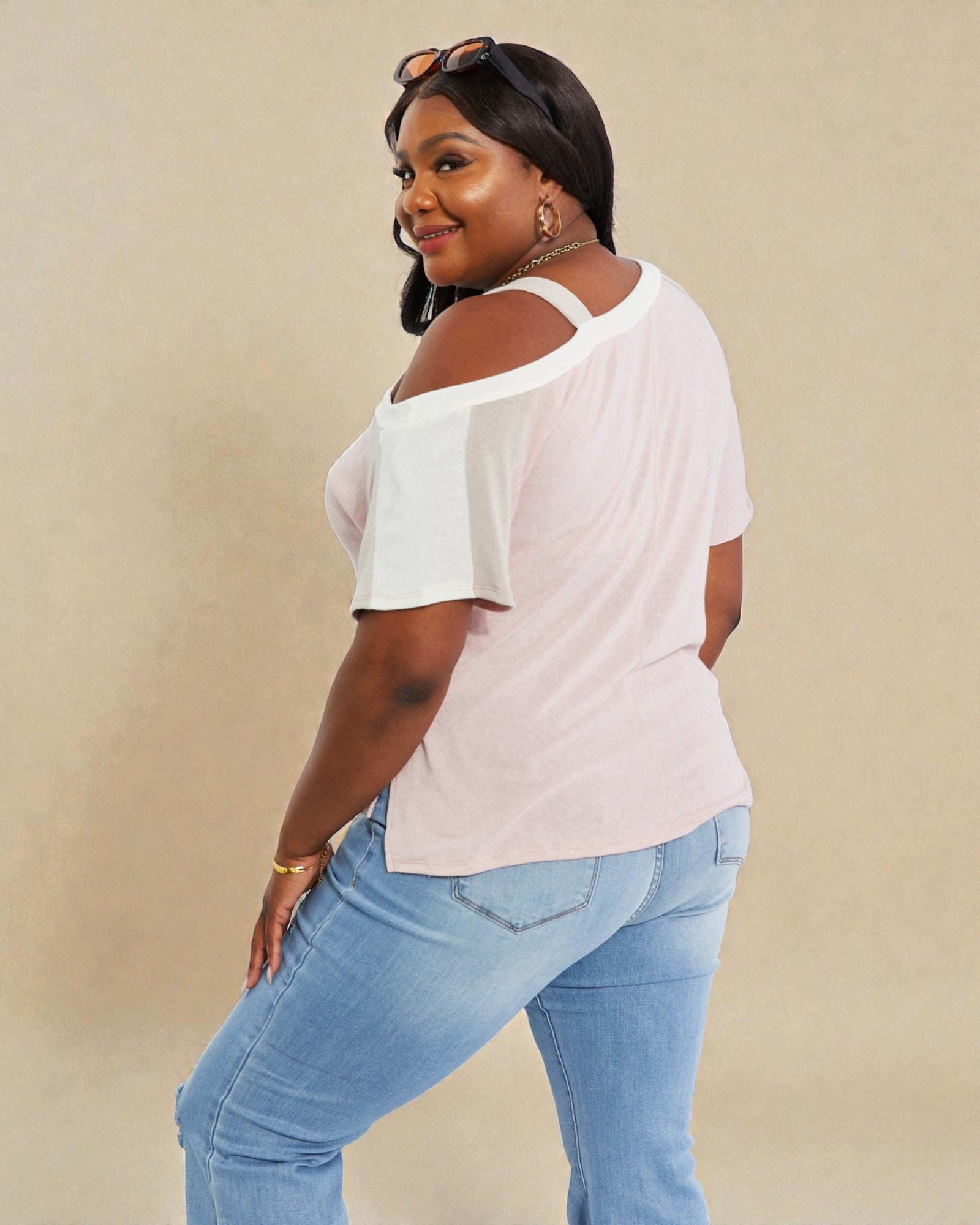 Woman wearing a white top and blue jeans against a beige background