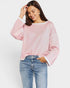 Woman wearing a pink sweatshirt with white trim and blue jeans on a light gray background