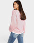 Woman wearing a pink sweater and blue jeans on a white background