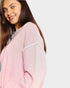Woman wearing a light pink sweater with a plain background